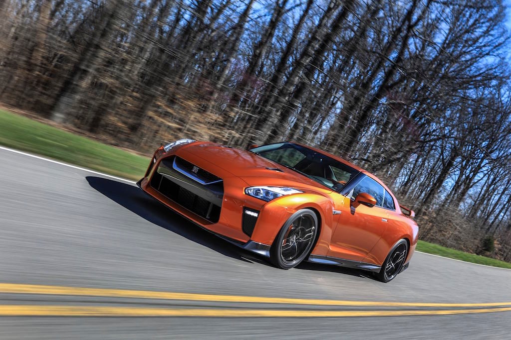 The 2017 GT-R's exterior receives a thorough makeover. The new V-motion grille, one of Nissan's latest design signatures, has been slightly enlarged to provide better engine cooling and now features a matte chrome finish and an updated mesh pattern. A new hood, featuring pronounced character lines flowing flawlessly from the grille, has been reinforced to enhance stability during high-speed driving. A freshly designed front spoiler lip and front bumpers with finishers situated immediately below the headlamps give the new GT-R the look of a pure-bred racecar, while generating high levels of front downforce.
