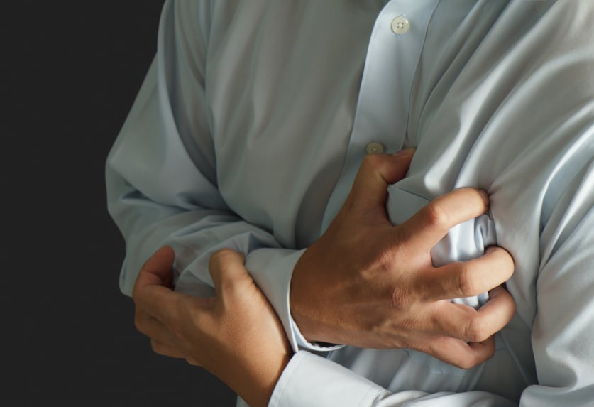 close-up of a man clutching his chest to show a heart attack