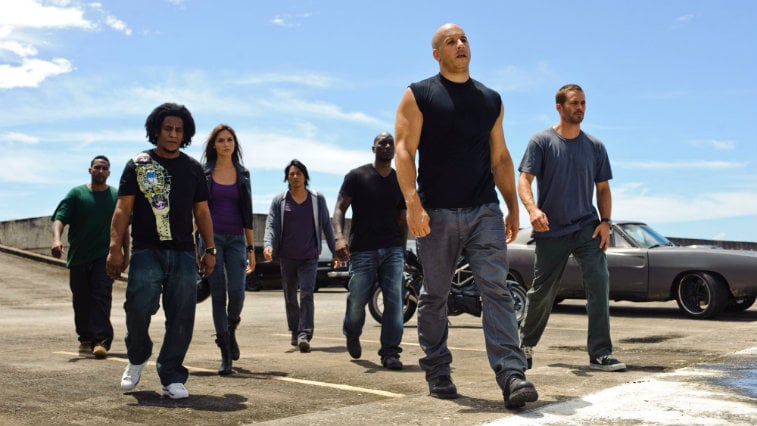 The cast of Fast Five walks away from their cars looking serious