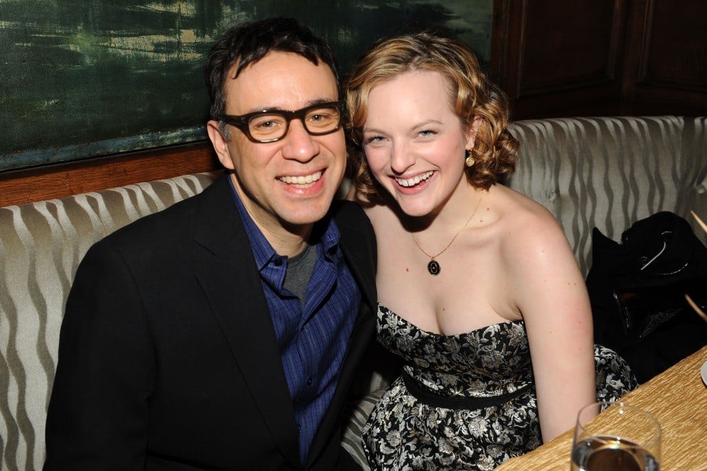 Fred Armisen and Elisabeth Moss sitting in a restaurant booth and smiling for the camera