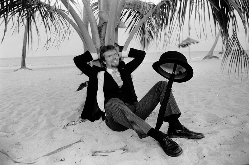 Billionaire Richard Branson sitting on beach
