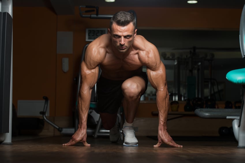 muscular man at the gym kneeling on one leg with his hands on the ground