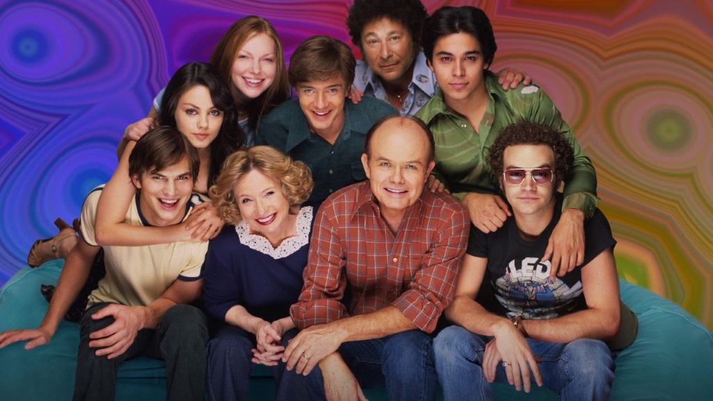 The cast of That '70s Show huddled together with a psychedelic backdrop