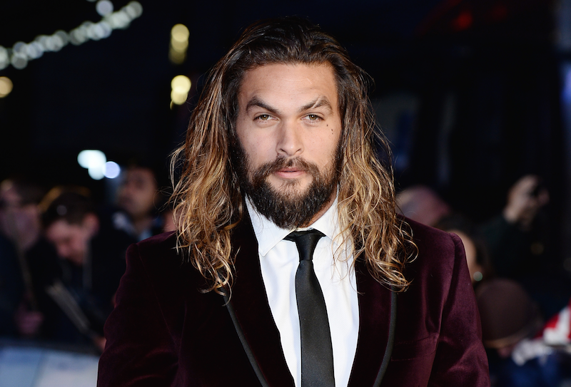 Jason Momoa wearing a suede suit at an event. 