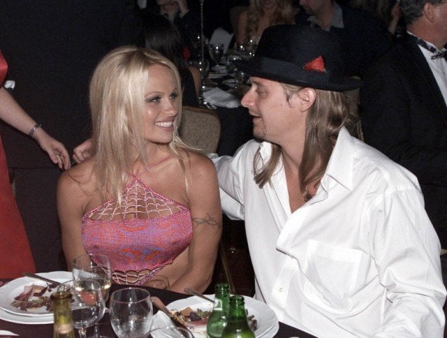 Pamela Anderson and Kid Rock smiling at each other while eating dinner together