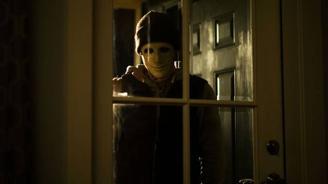 An unwelcome man stands watching in a window in a scene from the SXSW hit 'Hush'
