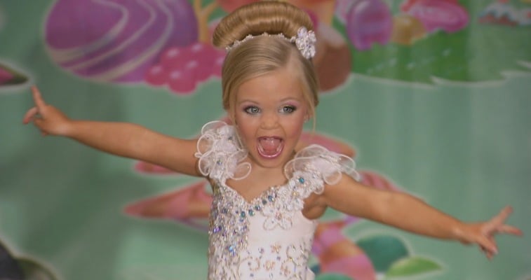 There is a blonde girl posing in a pageant dress. There is a blonde girl posing in a pageant dress.