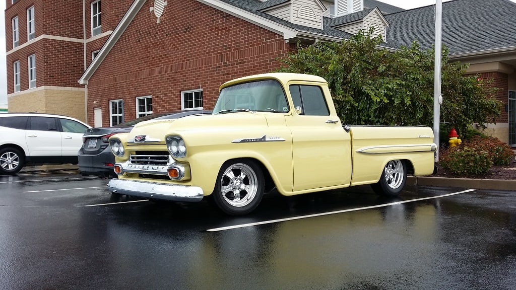 A canary yellow Chevy Apache Fleetside sits parked in a designated parking spot