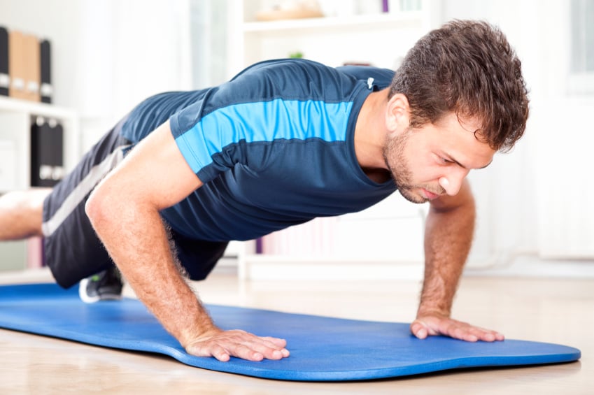 Man doing plank position on a mat at home Man doing plank position on a mat at home