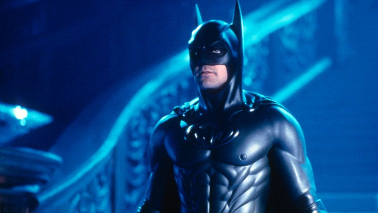 George Clooney wears a Batman suit and stands at the bottom of stairs in Batman and Robin