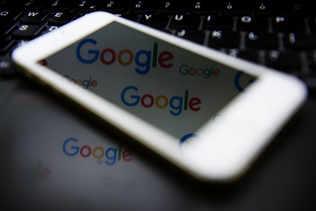 Smartphone refelecting Google logos on a laptop