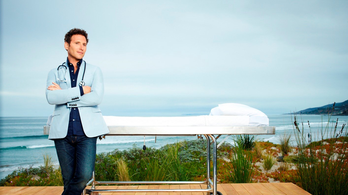 Mark Feuerstein stands on a beachside deck in a promotional poster for Royal Pains