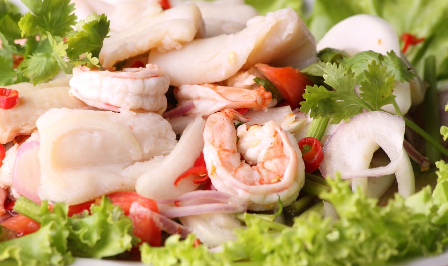 close-up of a Thai seafood salad with lettuce and fresh herbs