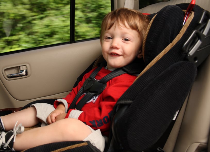 smiling toddler sitting in a front-facing car seat
