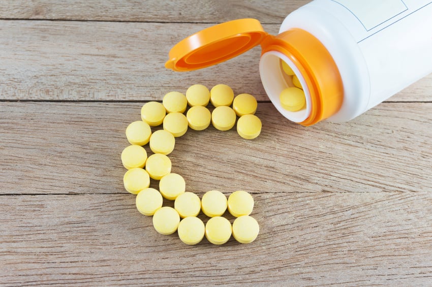 orange-yellow pills being poured from a bottle in the shape of a C