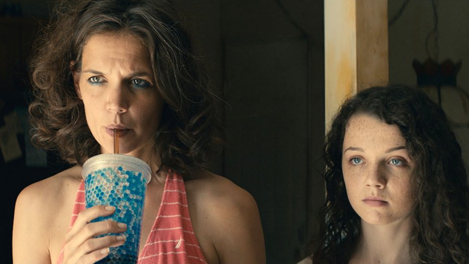 Katie Holmes sips on a soda next to a young girl in a scene from All We Had