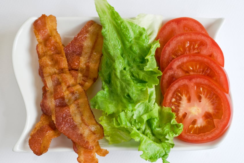 bacon, lettuce and sliced tomatoes on a white plate