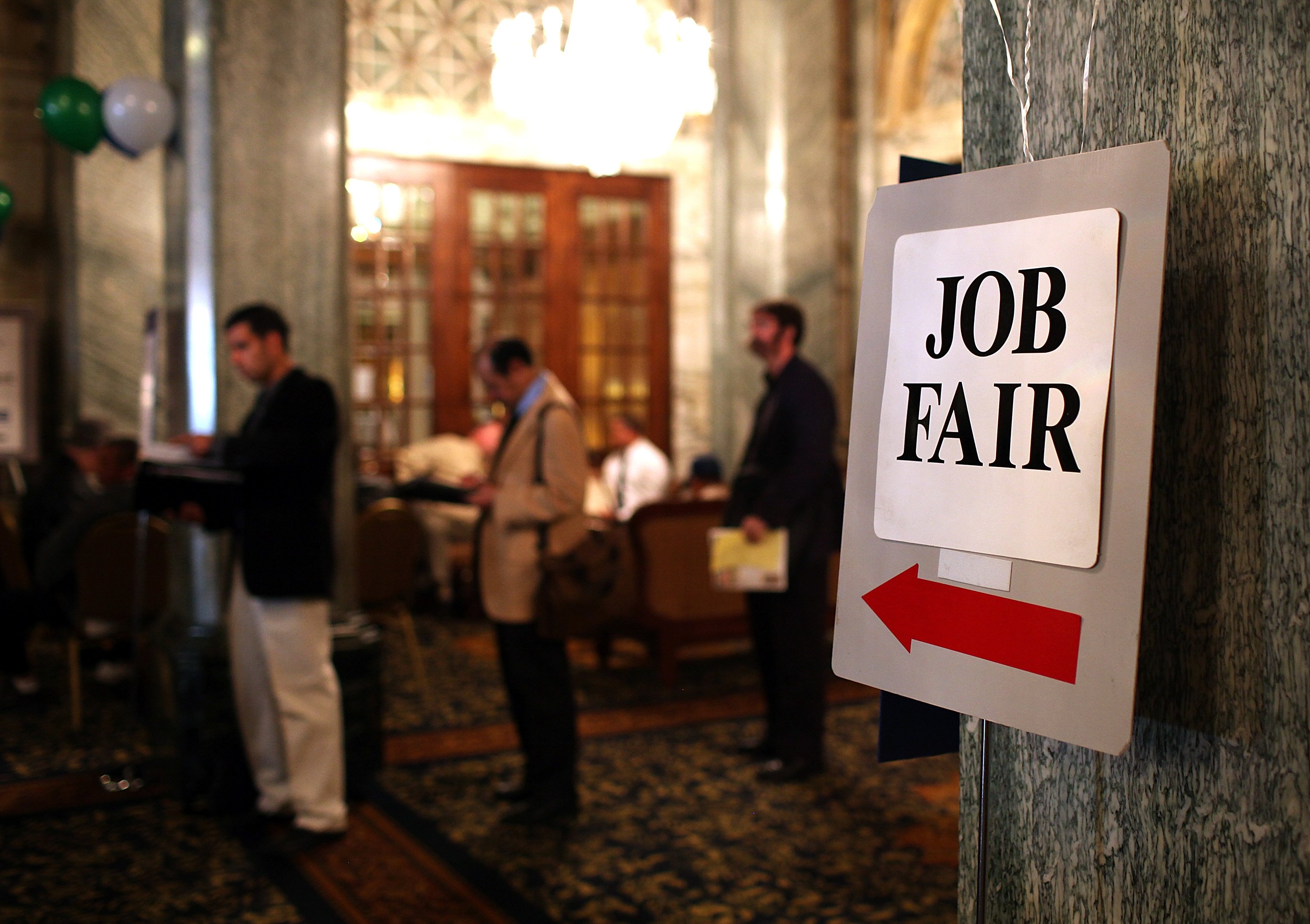 Job seekers wait in line to enter a job fair