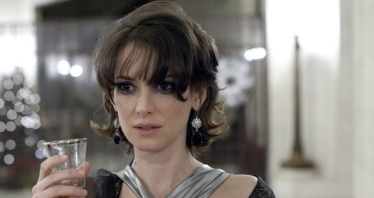 Winona Ryder is holding a wine glass as she is wearing a gown.