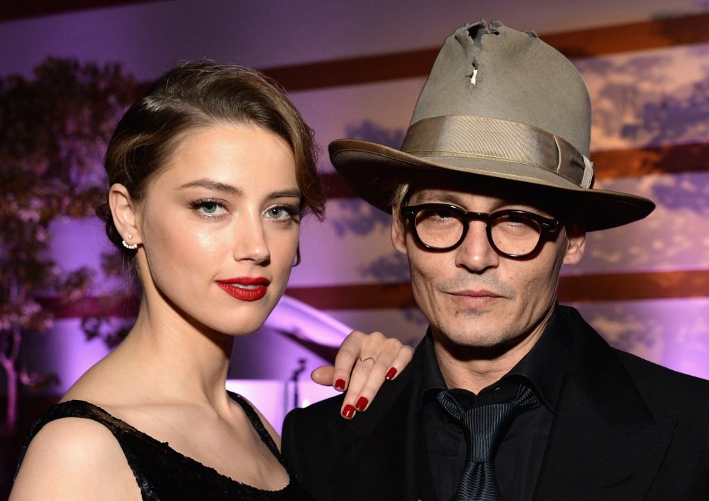 Amber Heard and Johnny Depp pose together and her hand is on his shoulder.