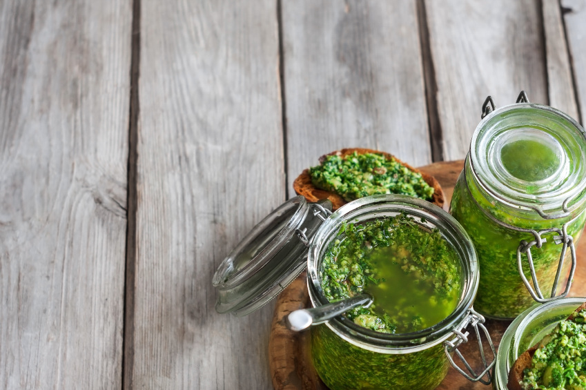 Cilantro pesto in jars on wooden background