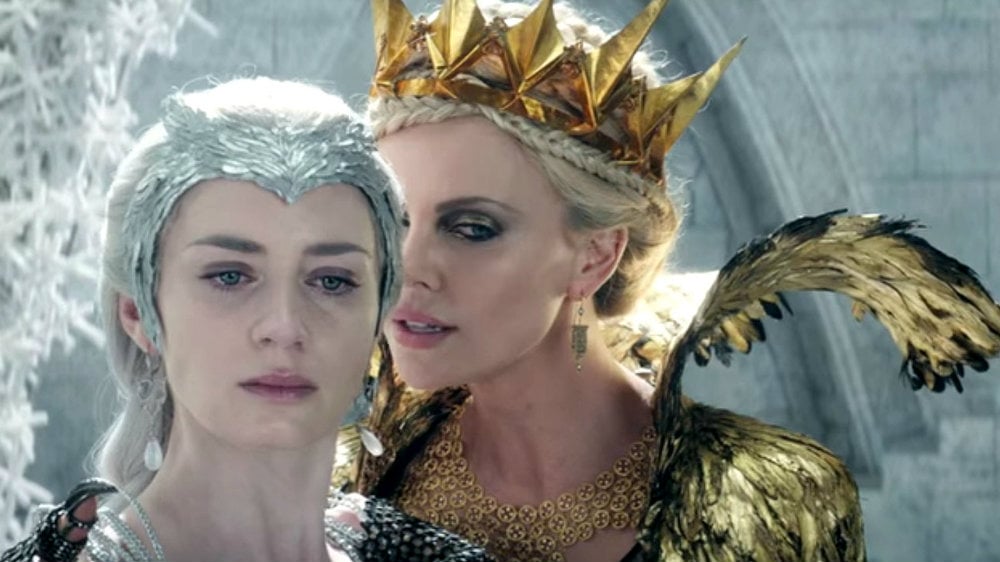 Charlize Theron as Queen Ravenna whispering in the ear of her sister, Freya the Ice Queen, played by Emily Blunt in The Huntsman Winter's War