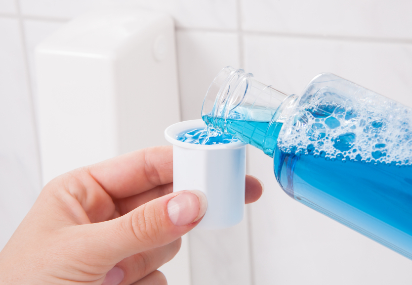 man pouring mouth wash from bottle to bottle cap