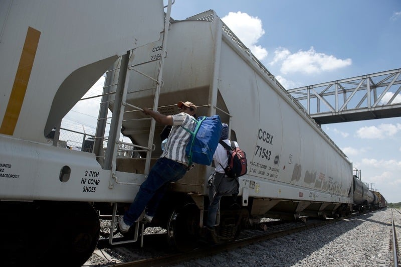 Two Honduran migrants hop a train