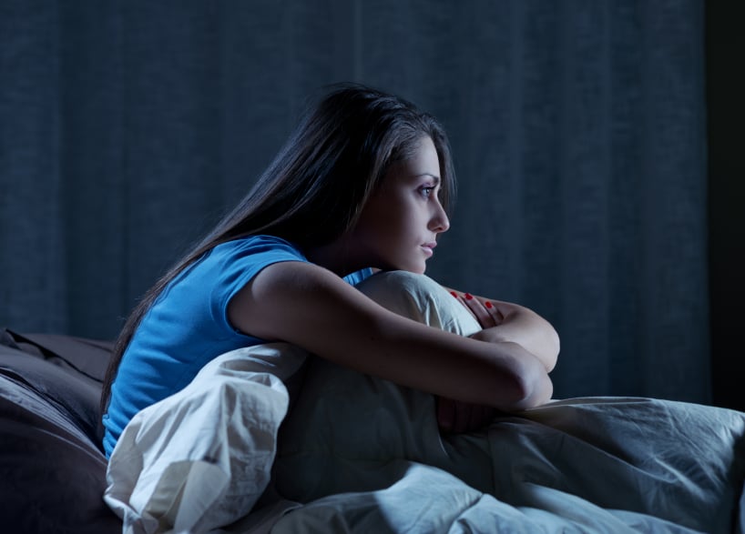 young woman sitting up in bed at night