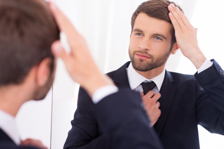 young attractive man looking at himself in mirror
