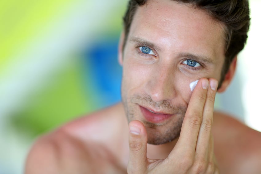 young man applying cream on his face