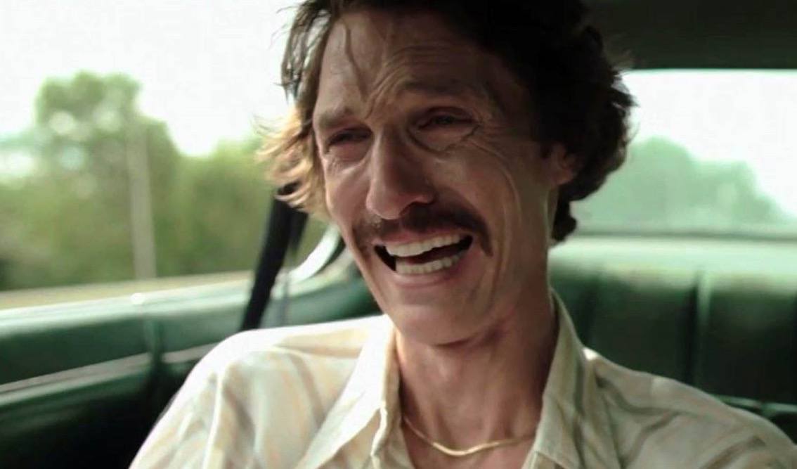 Matthew McConaughey with a mustache, crying in the front seat of a car