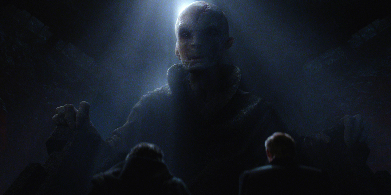 Supreme Leader Snoke, half-lit, sits in a large chair, looking down at the camera