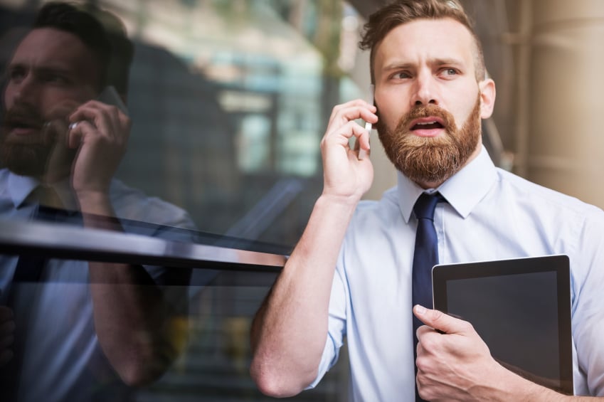 man blindsided by news at work on the phone