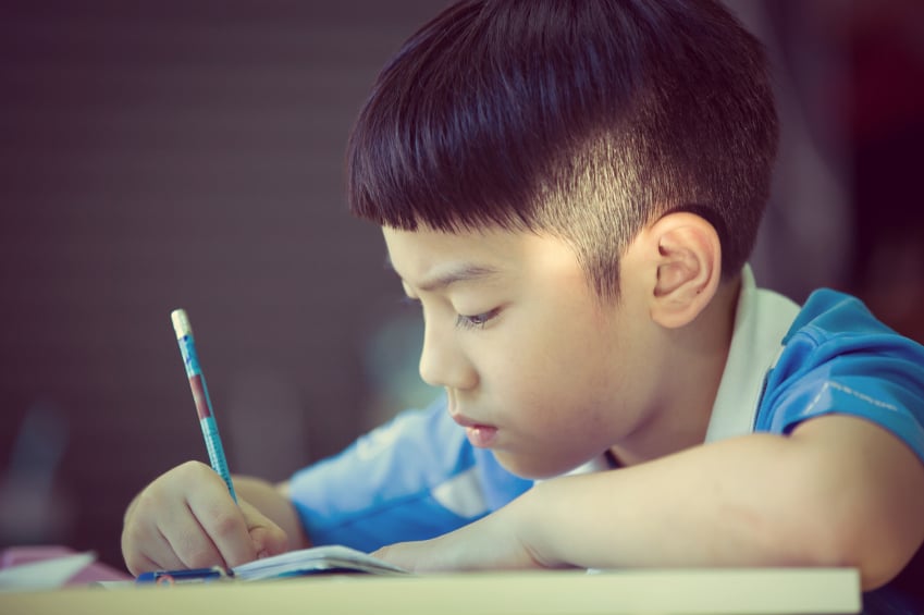 young boy writing a letter or doing his homework