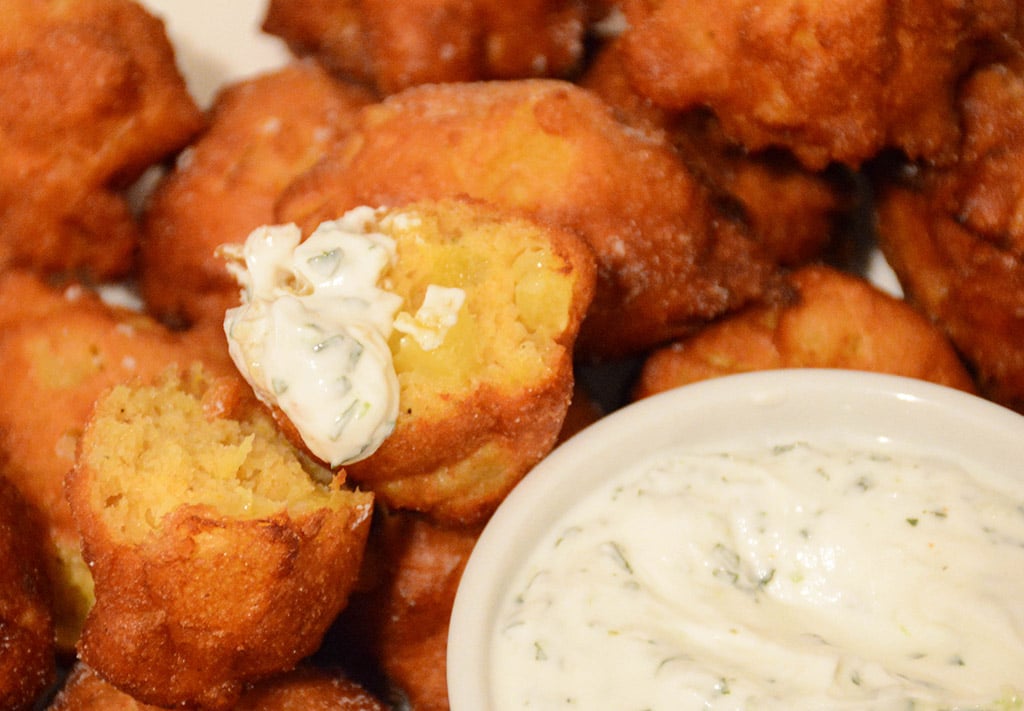 close-up of a curried pineapple fritter dunked in mint-lime yogurt