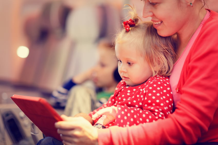 mother and little daughter looking at touch pad in plane