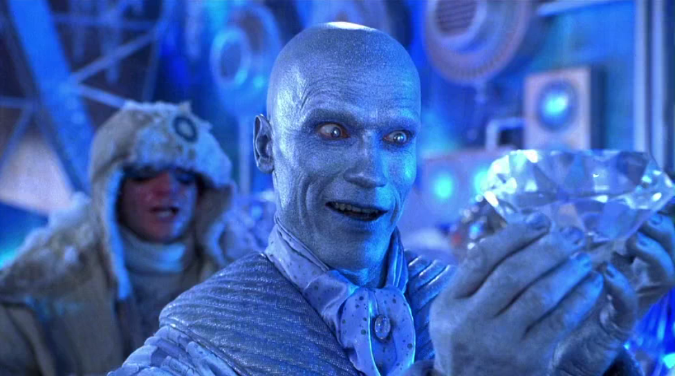 Mr. Freeze, with blue skin and a blue suit, smiling intently as he looks at a large diamond held in his hands