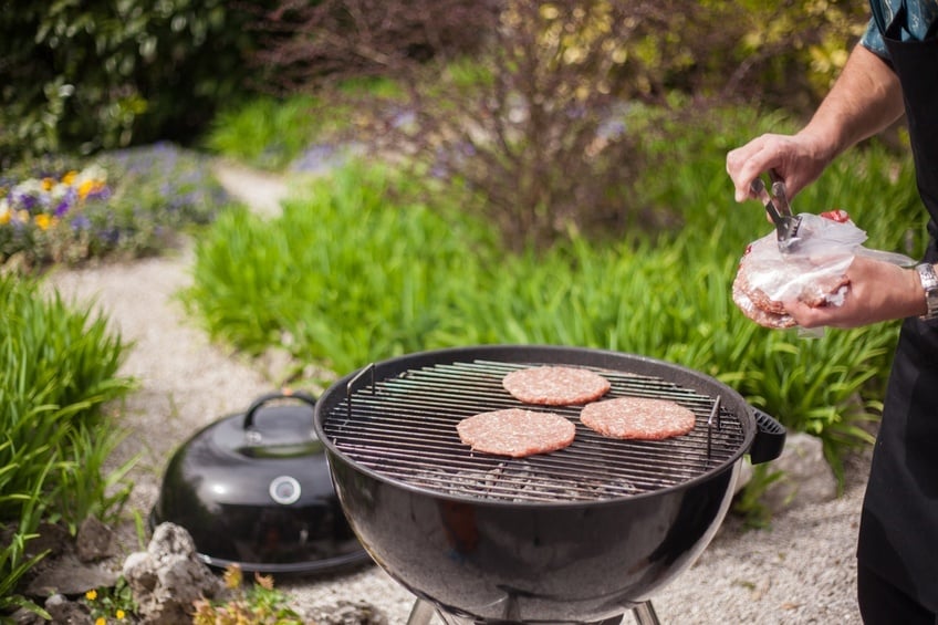 man preparing burgers on a charcoal grill