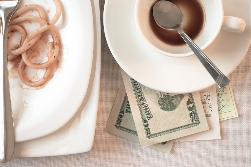 dollar bills under empty tea cup