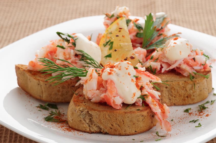 Crab meat with toast in a white plate