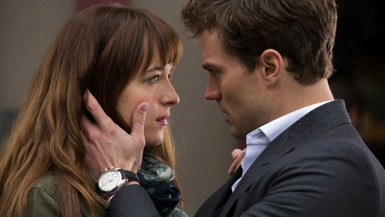 Jame Dornan holding Dakota Johnson's face in his hands, gazing into her eyes intensely