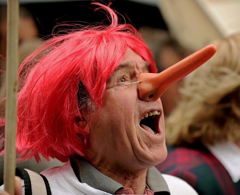 A man wears a 'Pinocchio' style nose, emulating the most famous liar of all time