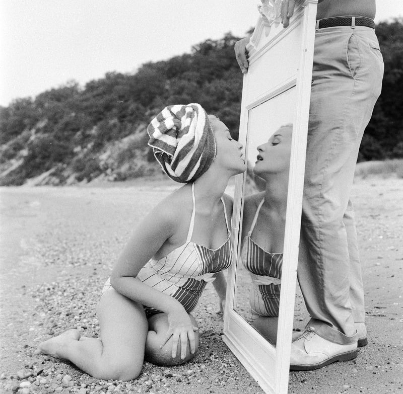 A narcissistic girl on a beach checking her lipstick in a mirror A narcissistic girl on a beach checking her lipstick in a mirror