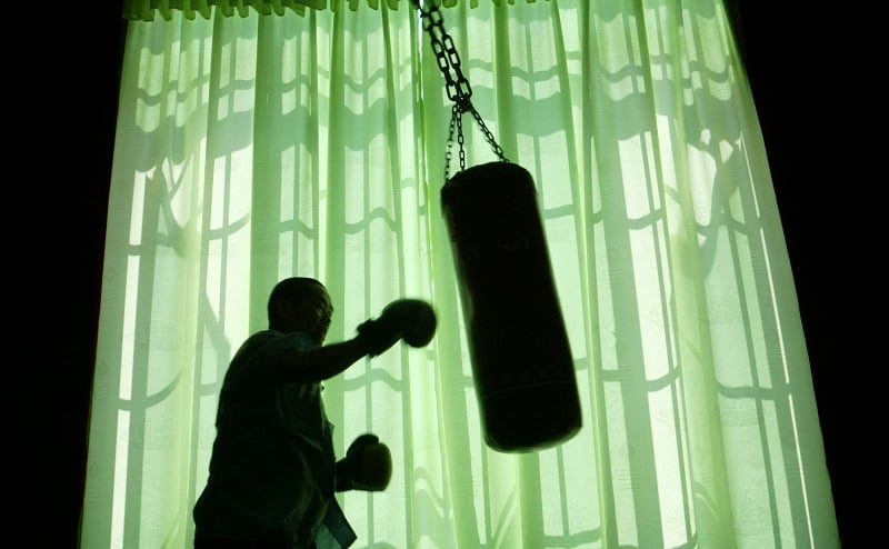 An older man works toward his fitness goals by hitting a punching bag