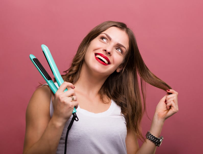 woman styling hair with a heated hair straightener