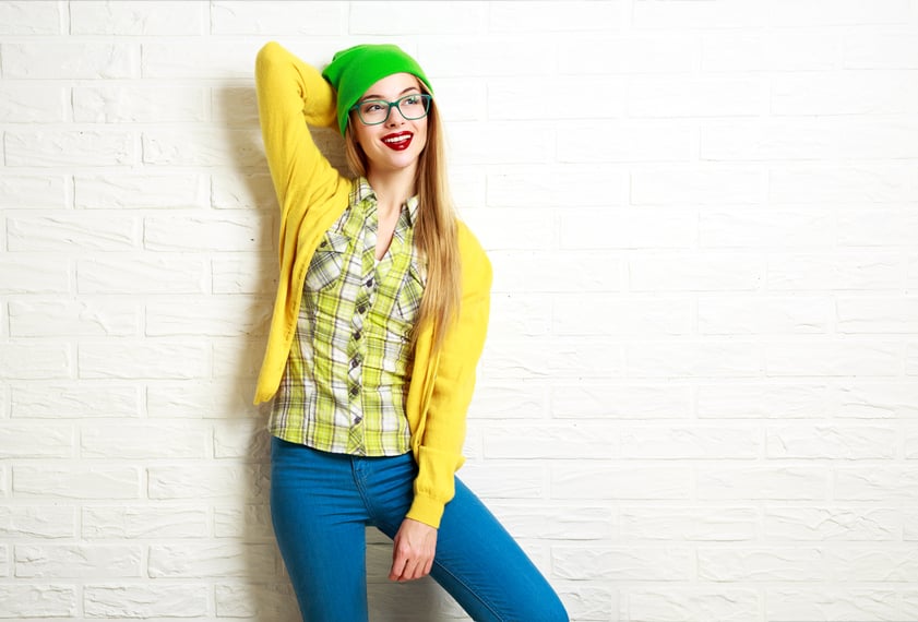 Happy hipster girl standing against the wall
