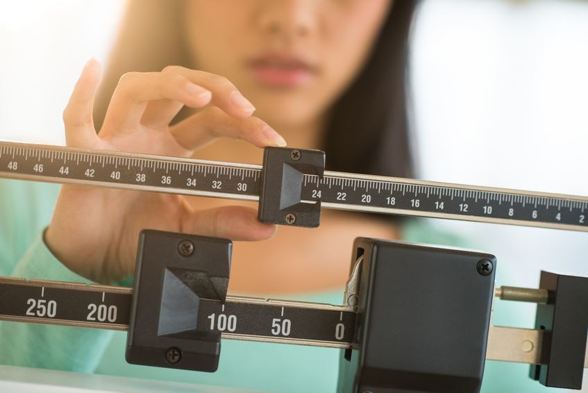 Woman Adjusting Weight Scale Woman Adjusting Weight Scale