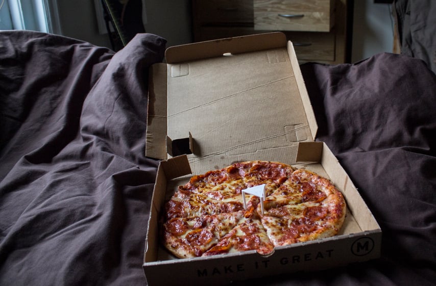 Pizza in a box on bed
