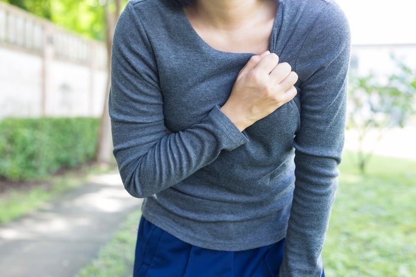 woman clutching her chest while walking outside